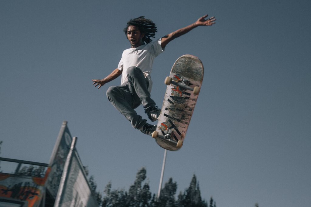 Skater laver et hop over en rampe i en udendørs skatepark