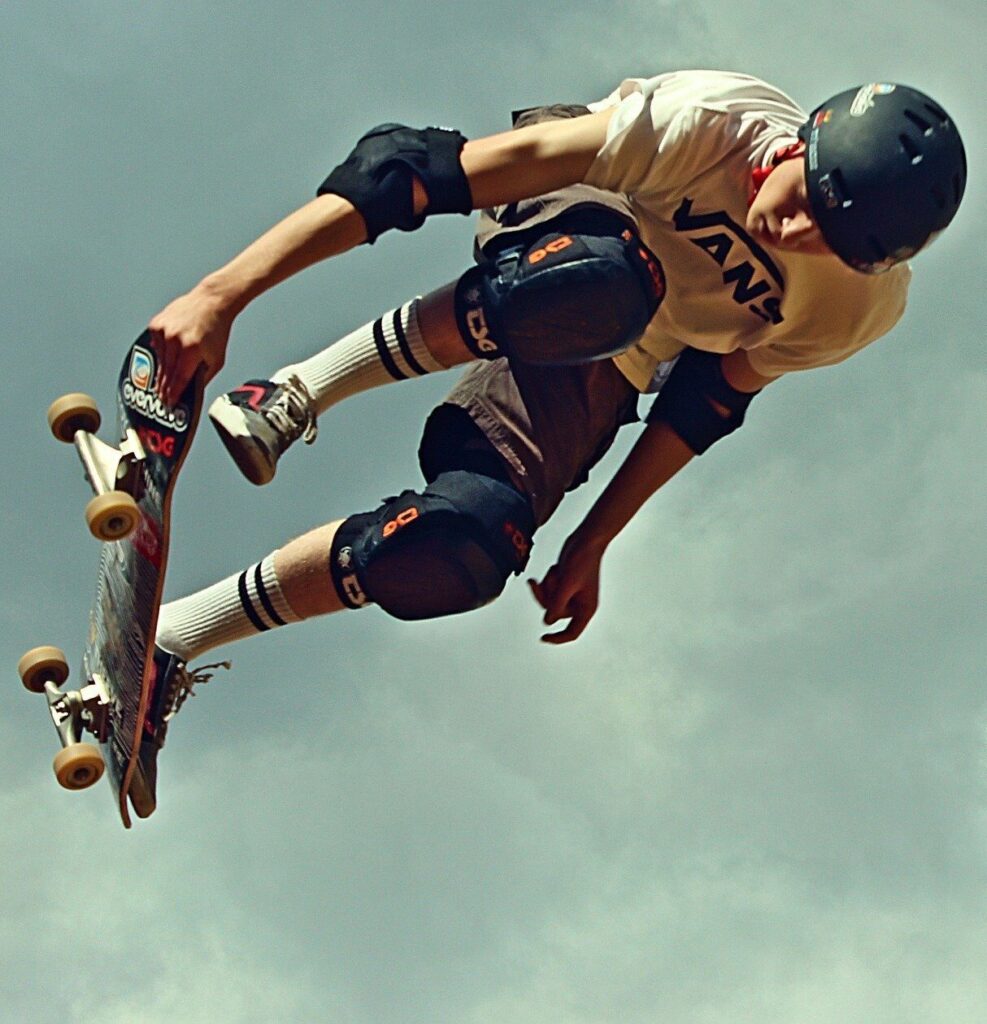 Skater med hjelm og beskyttere laver et hop med skateboard
