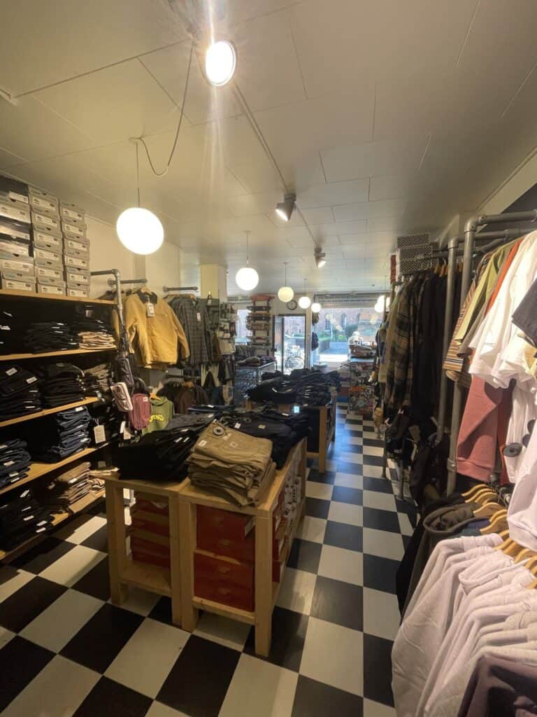 Bukser, jakker og T-shirts langs gangen i Skate House