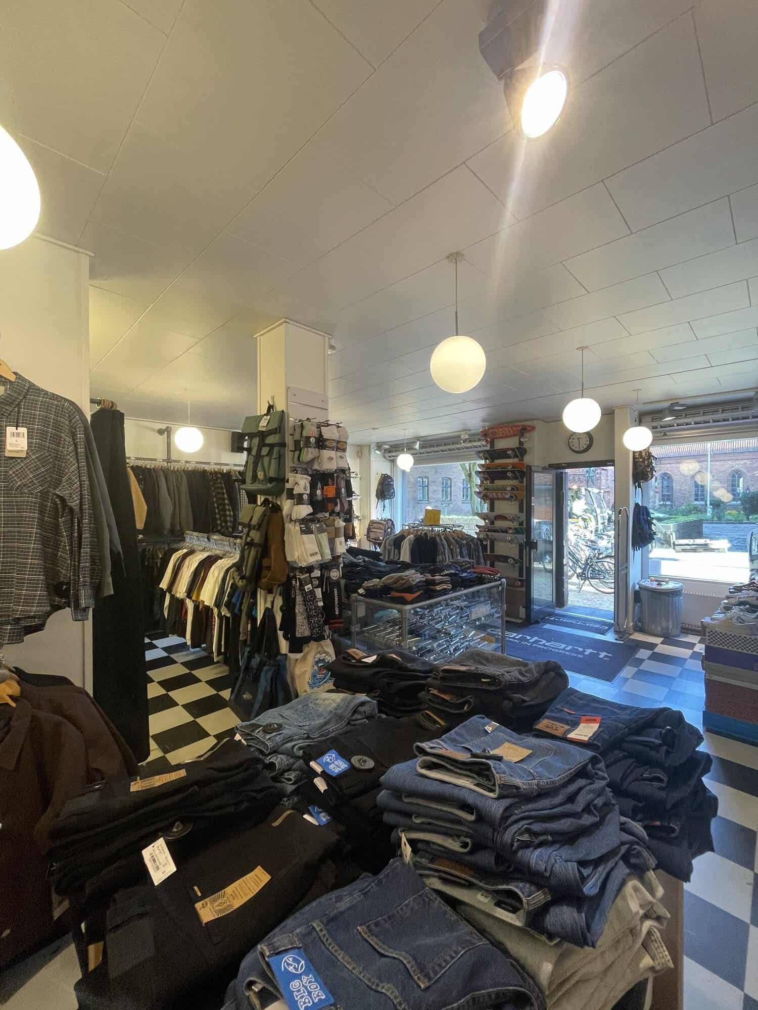 Jeans og tøjstativer med kig mod indgangen til Skate House